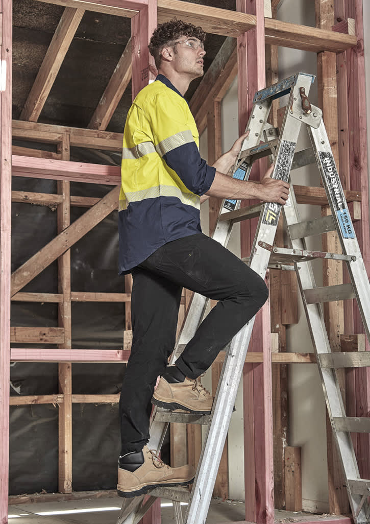 Lightweight black cargo pants worn by a man climbing a ladder in a building under construction.