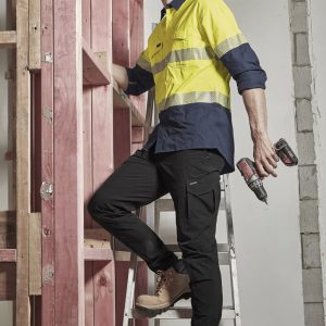 Mens lightweight outdoor pant in black, paired with safety boots, on a ladder in a construction setting. Features a logo.