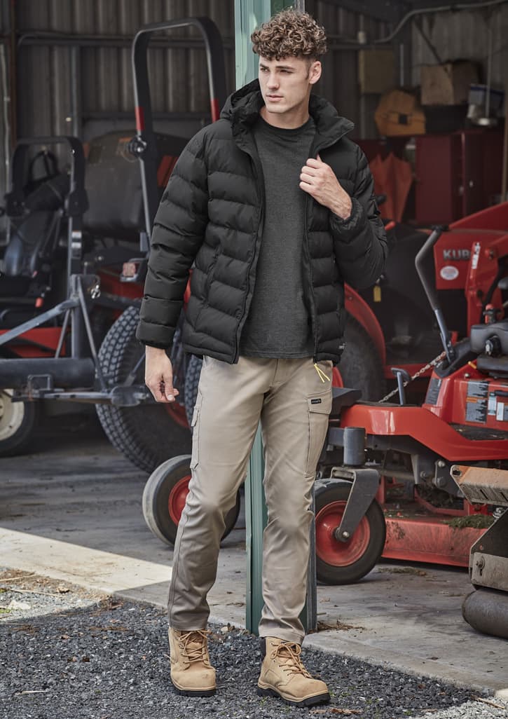 Men's essential basic stretch cargo pants in beige, paired with a black puffer jacket and tan boots, set in an outdoor environment.