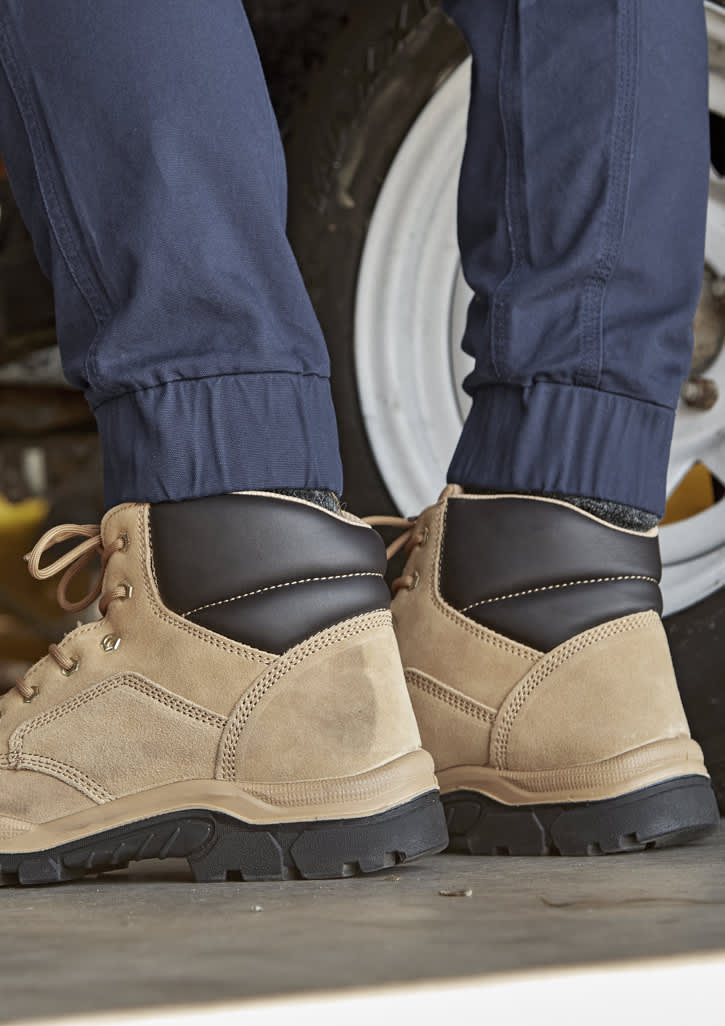 A pair of cuffed navy work pants worn with tan and black boots, set against a vehicle backdrop.