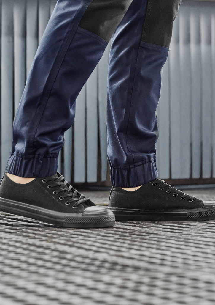 A pair of navy work pants with black accents, worn with black casual shoes on a patterned floor.
