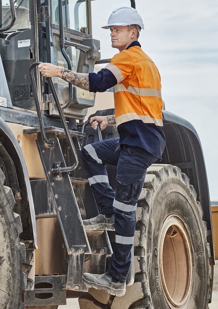 Men's rugged work pants in navy and orange, featuring reflective tape and a logo, worn by a worker climbing machinery.
