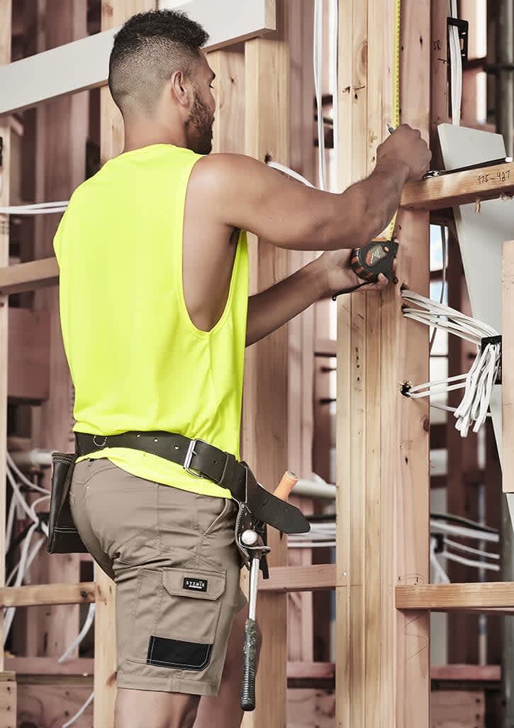 Men's summer cargo shorts in khaki, featuring multiple pockets, worn by a person in a bright yellow sleeveless top.
