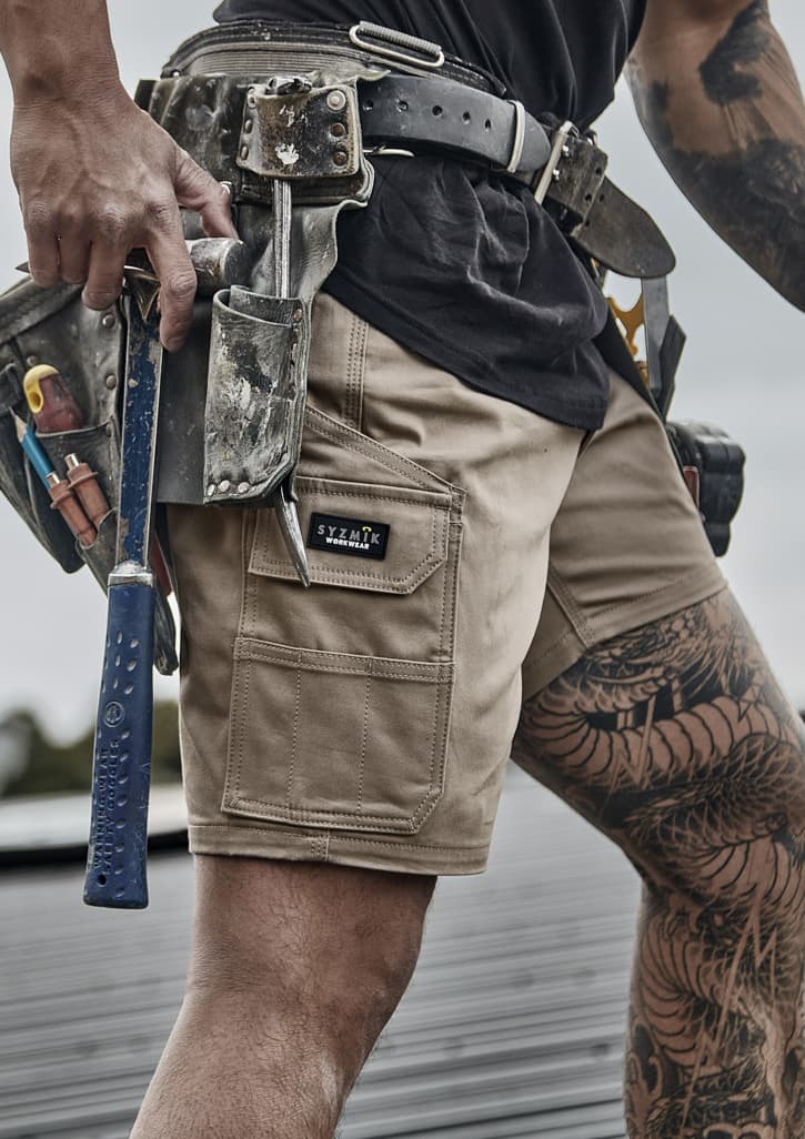Men's essential stretch cargo shorts in light brown, featuring multiple pockets and a branding label.