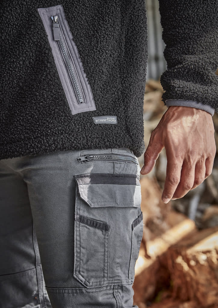 Unisex black Sherpa fleece with zippered pocket, paired with grey work pants featuring cargo pockets and branding.