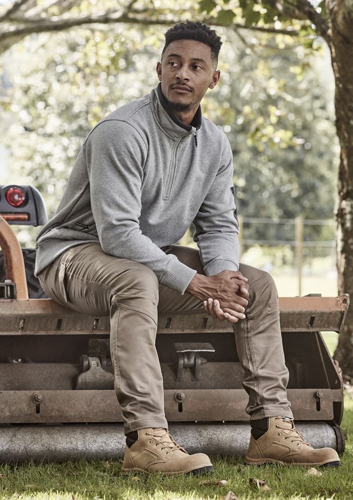 A unisex 1/4 zip brushed fleece pullover in grey, worn with khaki trousers and brown boots, featuring a logo.