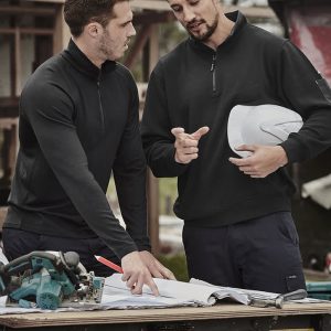 A black unisex Merino wool mid-layer pullover is worn by two men discussing plans at a construction site.