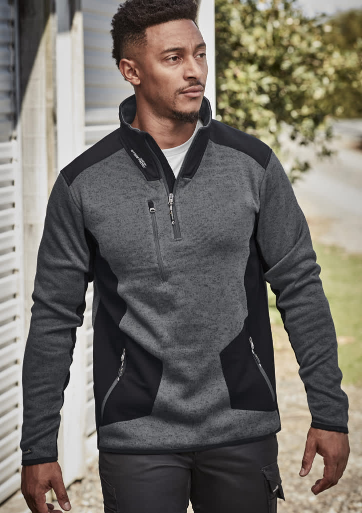 A man wears a grey and black Unisex Streetworx Reinforced Knit 1/2 Zip Pullover, featuring a zippered pocket and side pockets.