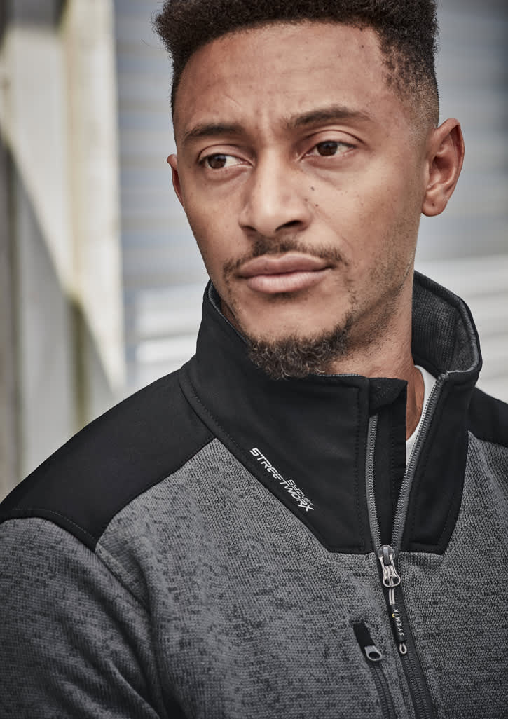 A man wearing a grey and black unisex ½ zip pullover with a reinforced knit design, featuring a logo.