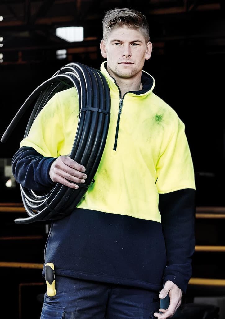 A unisex hi-vis yellow and navy polar fleece pullover with a half zip and a logo, held by a person with a cable.