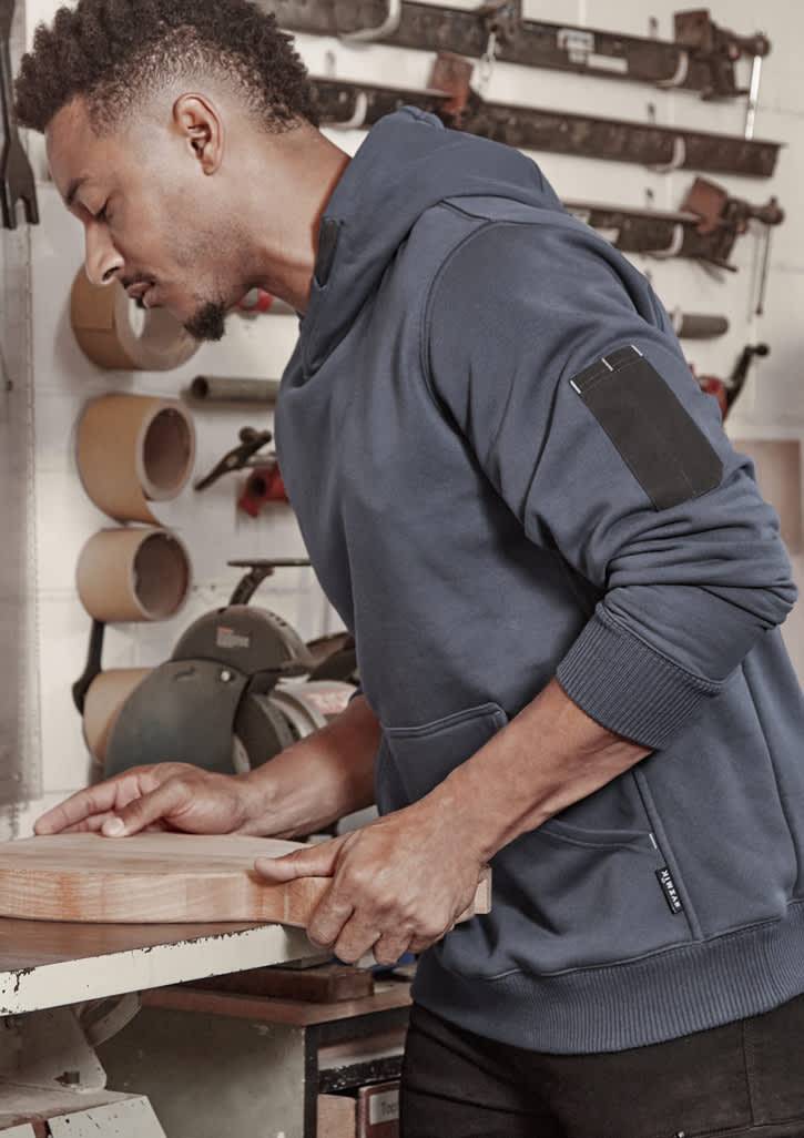 Unisex multi-pocket hoodie in navy, featuring a side pocket, worn by a person working in a workshop.