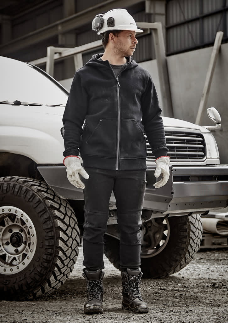 A man wearing a black unisex zip front multi-pocket hoodie, gloves, and work boots, standing next to a white vehicle.