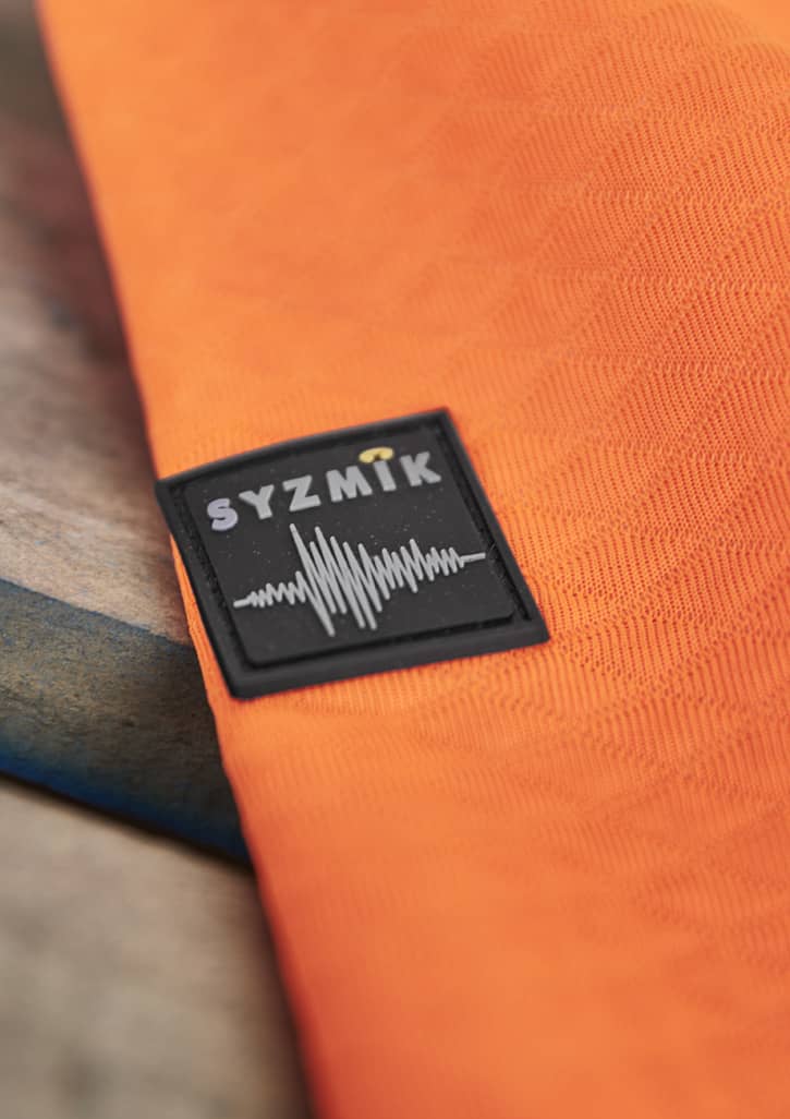An orange unisex hoodie with a textured jacquard design and a branded logo.