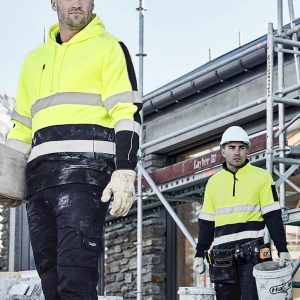 A high visibility yellow hoodie with black stripes, worn by two men on a construction site, featuring a logo.