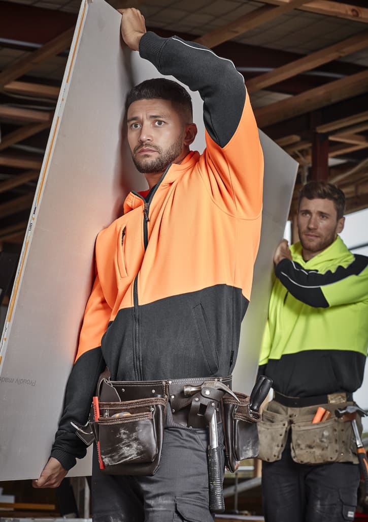 Unisex hi-vis full zip hoodie in orange and black, featuring a logo, worn by a model on a construction site.