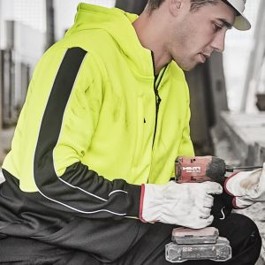 A unisex high visibility full zip hoodie in bright yellow with black accents, worn by a person holding a drill.