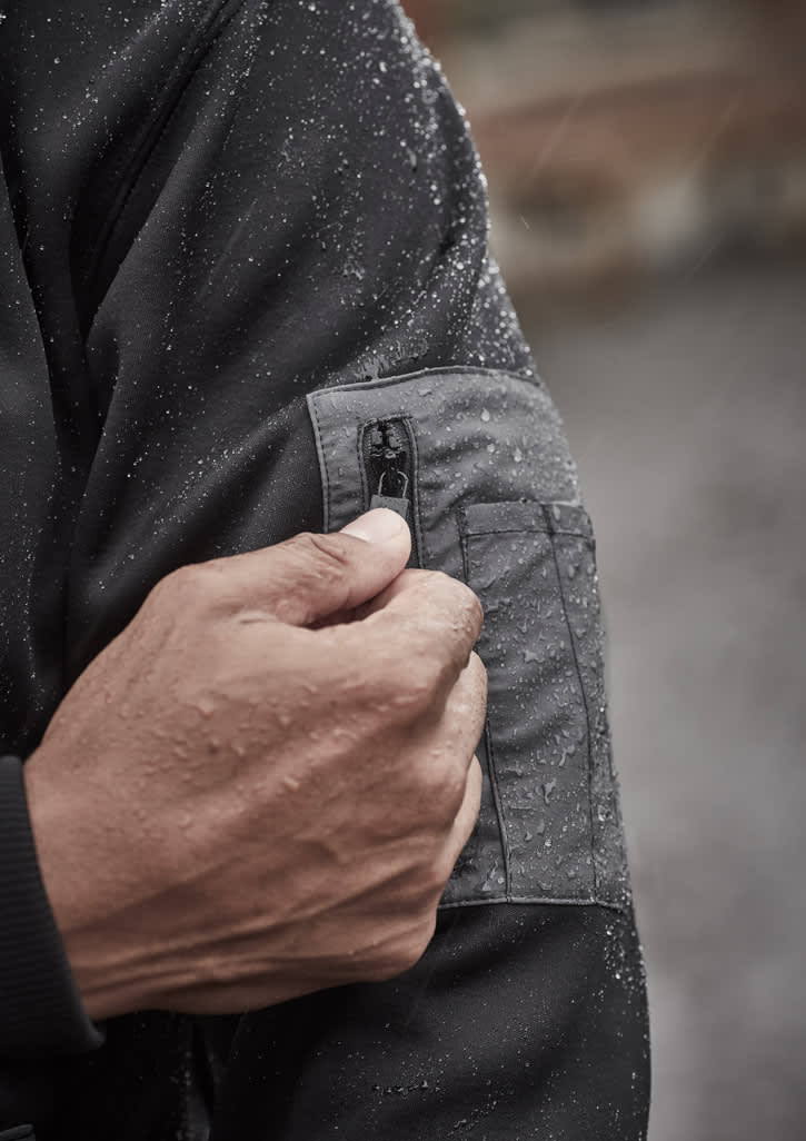 A black unisex water-resistant hoodie with a logo, featuring a front pocket and worn by a model holding wooden blocks.