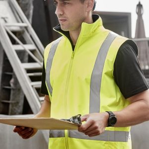 A man wearing a bright yellow waterproof reversible vest with reflective stripes, holding a clipboard.