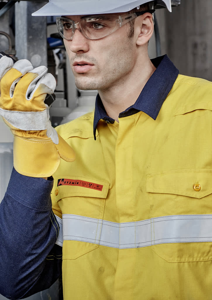 A lightweight work shirt in yellow and navy, featuring hoop tape, worn by a model with safety gear.
