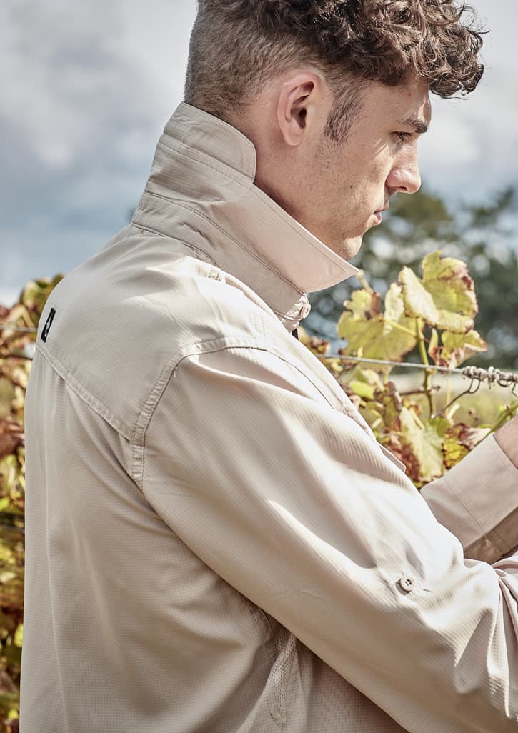 A light beige men's outdoor long sleeve button-up shirt, featuring a collared neck and a logo on the back.