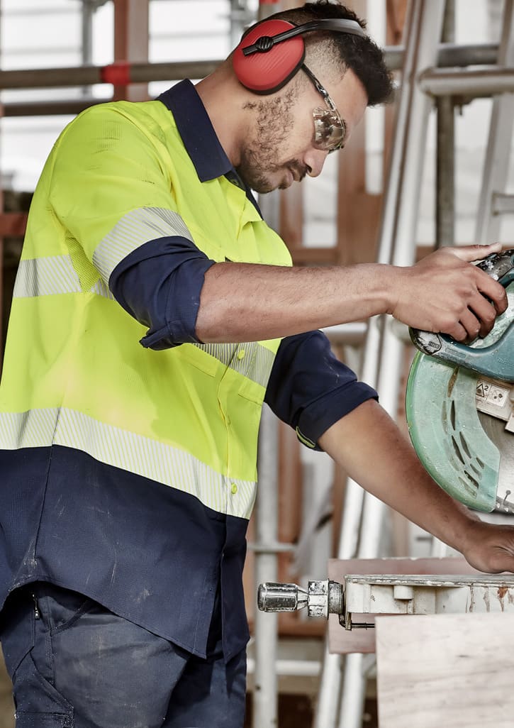 A segmented long sleeve work shirt in hi-vis yellow and navy, featuring reflective tape and a logo, worn by a male worker.