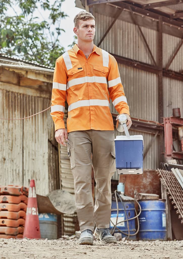 A man wears an orange long sleeve work shirt with reflective stripes, carrying a blue cooler in an outdoor setting.