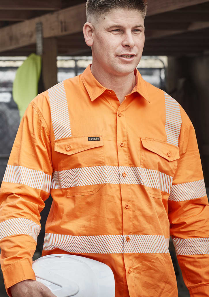 An orange long-sleeve work shirt with segmented reflective tape and a logo, worn by a man holding a white hard hat.