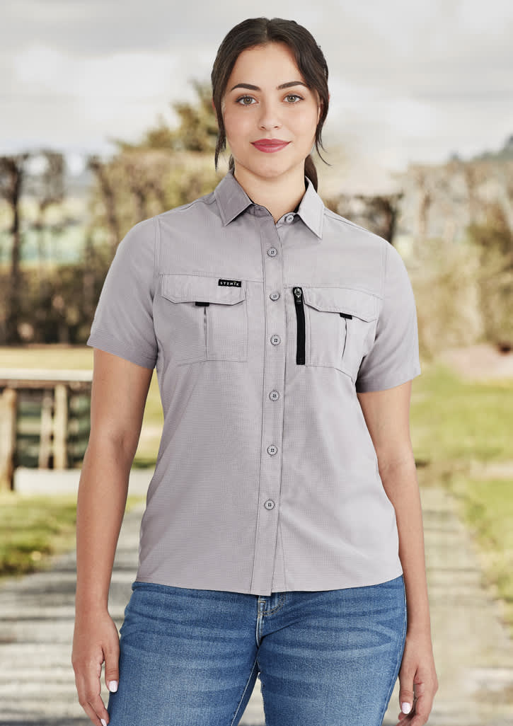 A light grey women's outdoor short sleeve shirt with chest pockets and a zipper pocket, featuring a logo.