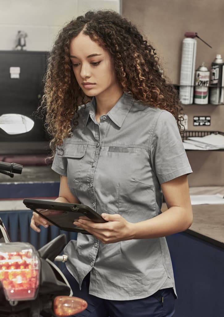 A navy short sleeve shirt with a button-up front and a pocket, featuring a logo on the label.