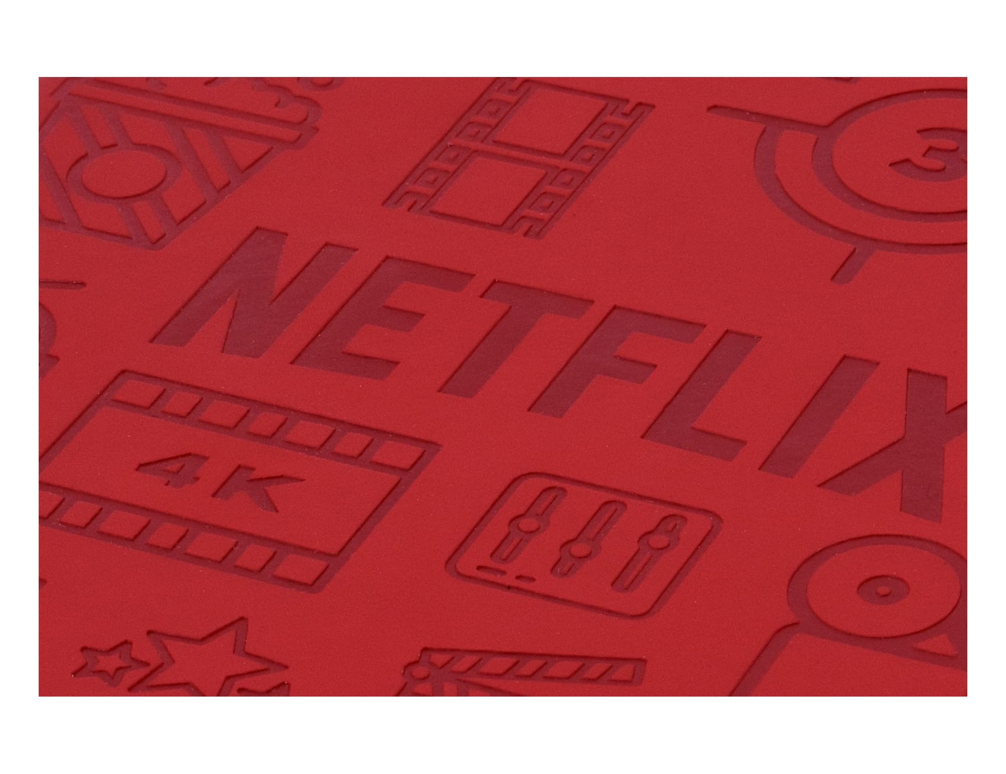 A red notebook with a debossed design featuring various icons related to film and entertainment, along with a logo.