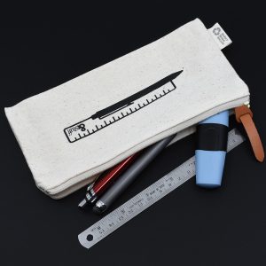 A cream-coloured pencil case with a ruler graphic, containing pens, a highlighter, and a ruler, with a leather zipper pull.