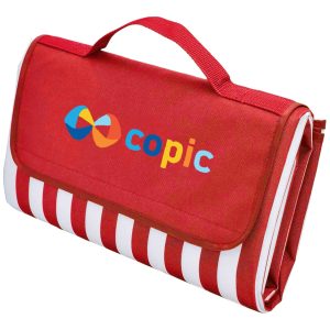A red picnic rug with a striped pattern and a handle, featuring a logo on the front.