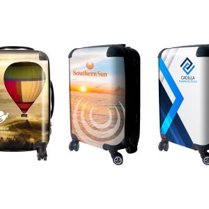 Three wheeled carry-on suitcases featuring colourful designs, including a hot air balloon, sunset, and abstract patterns.