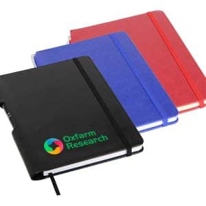 A set of three A5 notebooks in black, blue, and red, featuring an embossed logo on the black notebook.
