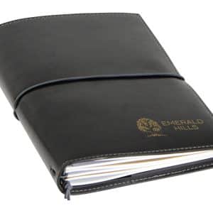 A black A5 journal with a smooth cover and a logo, featuring elastic closure and lined pages inside.