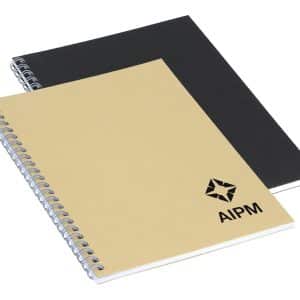 A spiral-bound A5 notebook in beige and black, featuring a logo on the front cover.