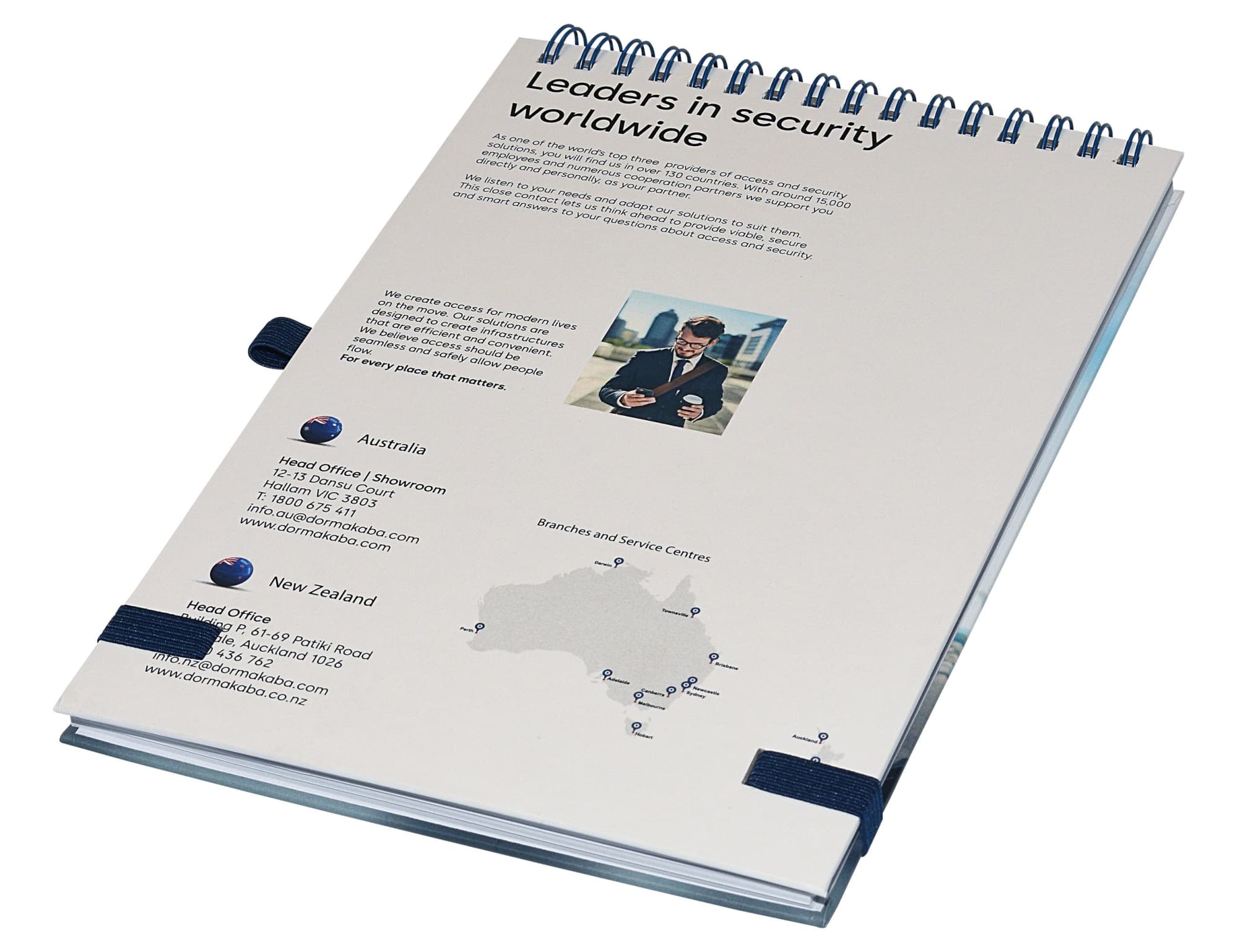 A light grey A5 notebook with a spiral binding, featuring a logo and contact information on the cover.