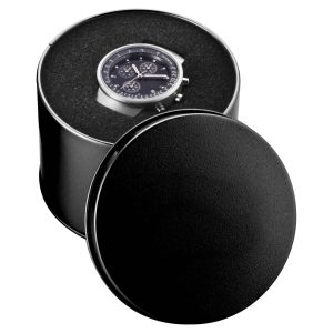 A round black watch case with a sleek watch displayed inside, featuring a dark watch face and metallic details.