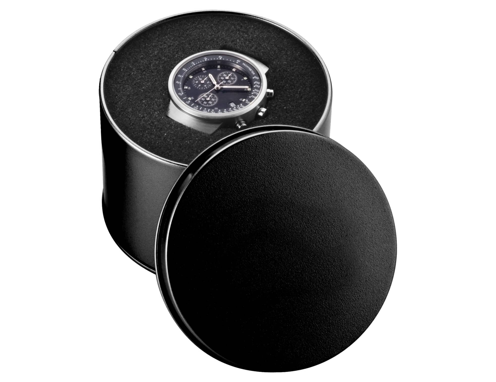 A round black watch case with a sleek watch displayed inside, featuring a dark watch face and metallic details.