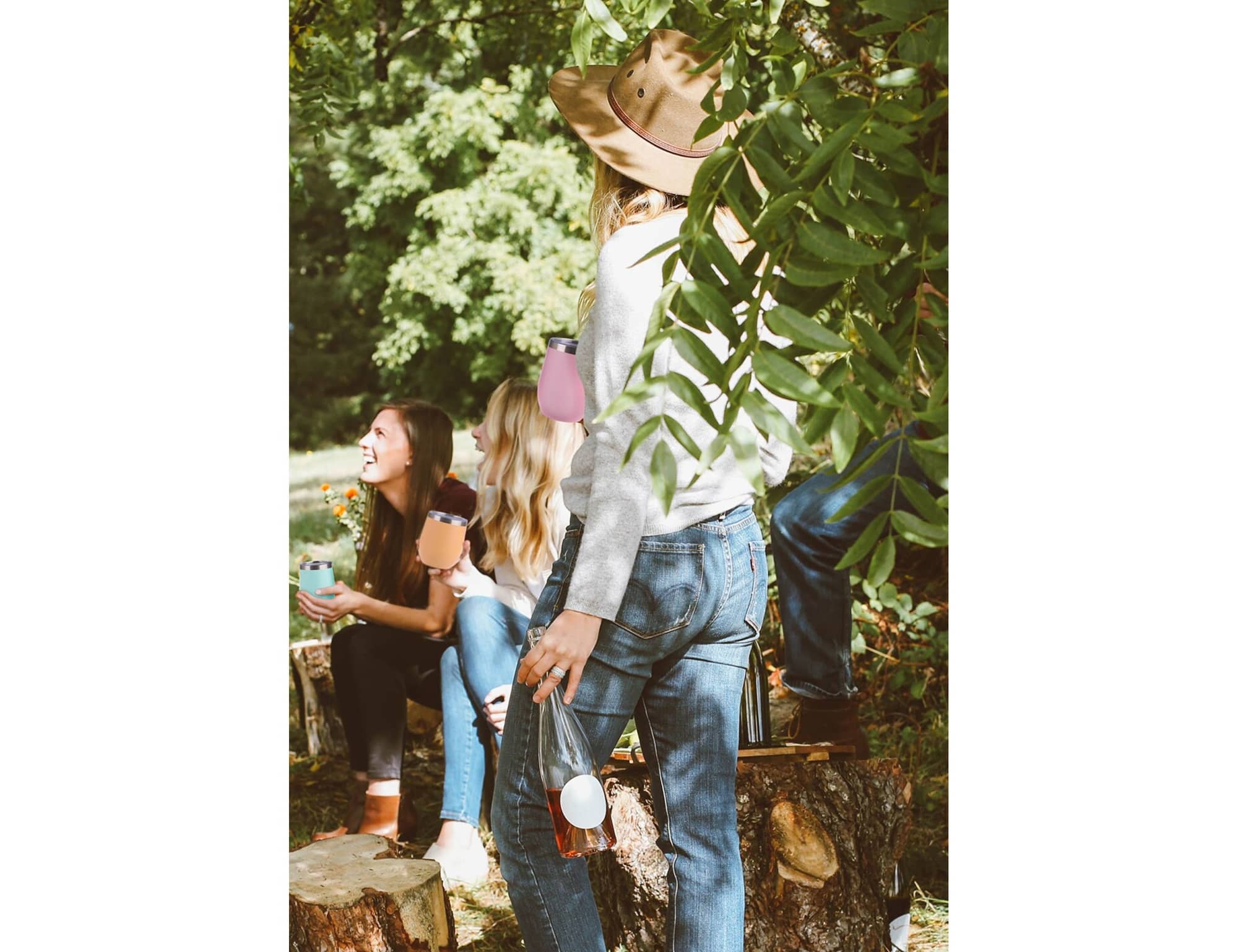 A group of people enjoying the outdoors, holding various drink tumblers, including a white and a colourful tumbler.