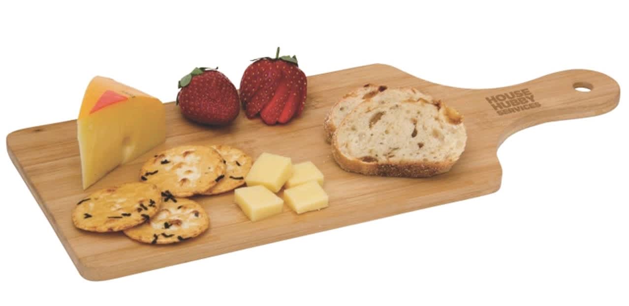 A wooden cheese board with slices of cheese, crackers, bread, and strawberries, featuring a logo on the handle.