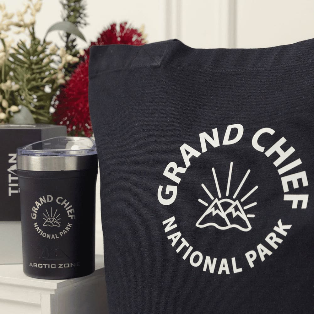 A black tote bag and a black drink container featuring a logo with mountains and sun graphics.