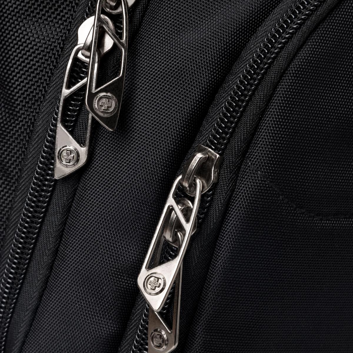 A close-up of silver zippers on a black backpack, showcasing textured fabric and a logo on the zipper pulls.