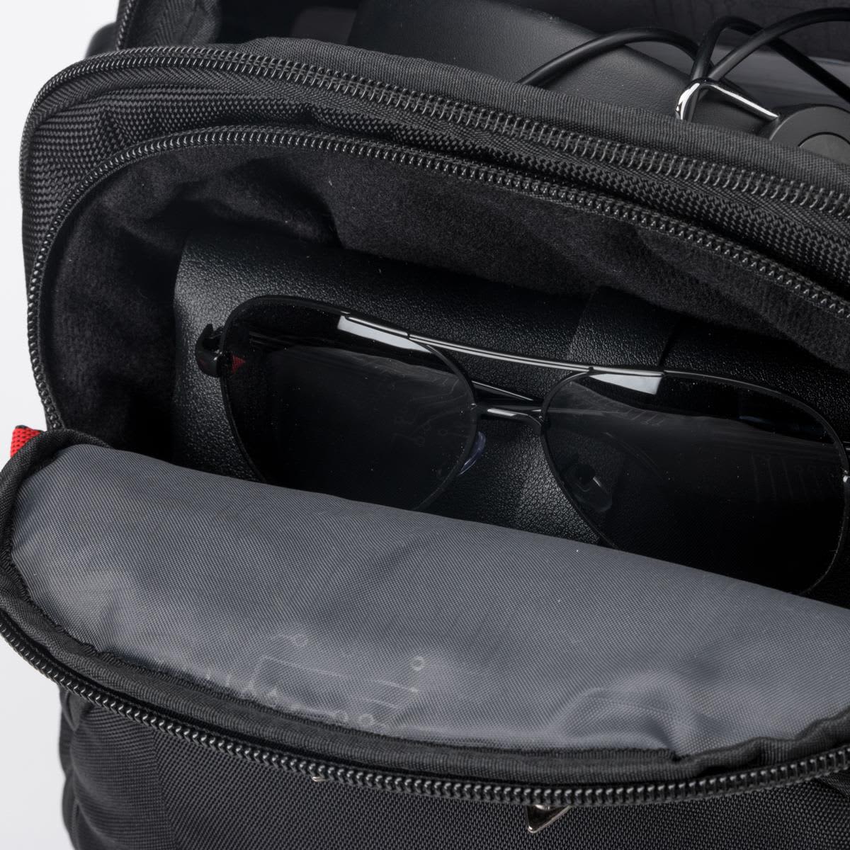 A black backpack with compartments, containing sunglasses and electronic devices. It features a branding logo.