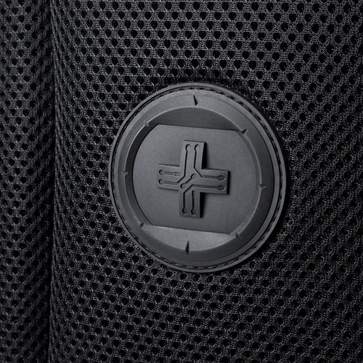 A close-up of a black mesh fabric featuring a round logo patch.
