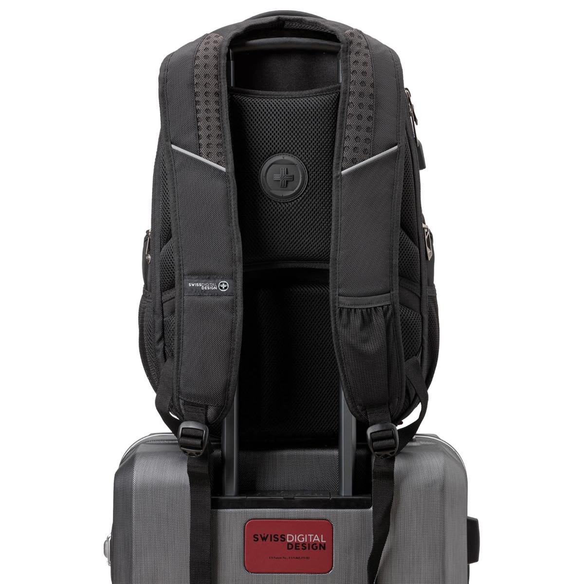 A black Swissdigital Stealth Neptune Backpack with padded straps and a logo, resting on top of a grey suitcase.