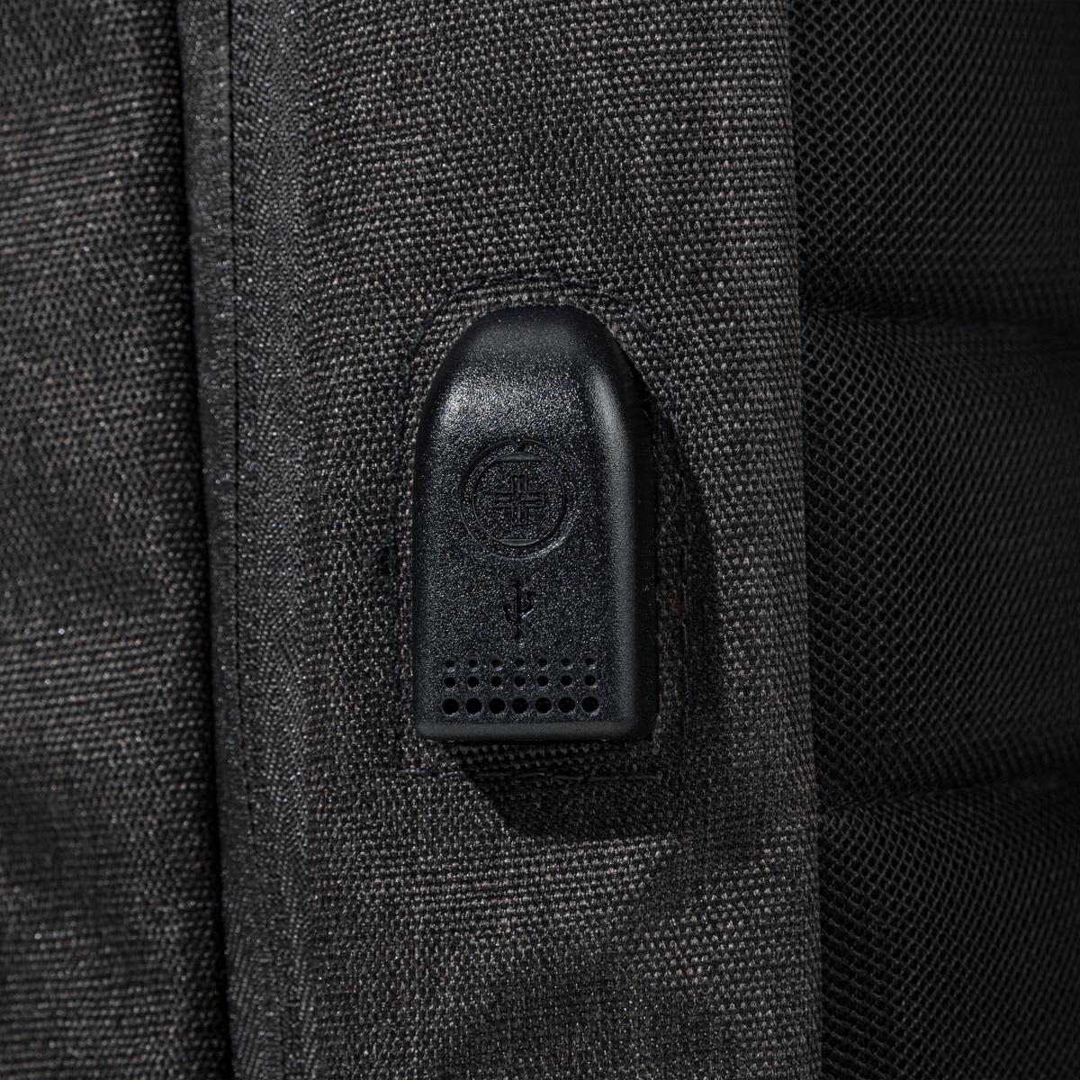 A close-up of a feature on a black backpack, showcasing a zipper pull and textured fabric.