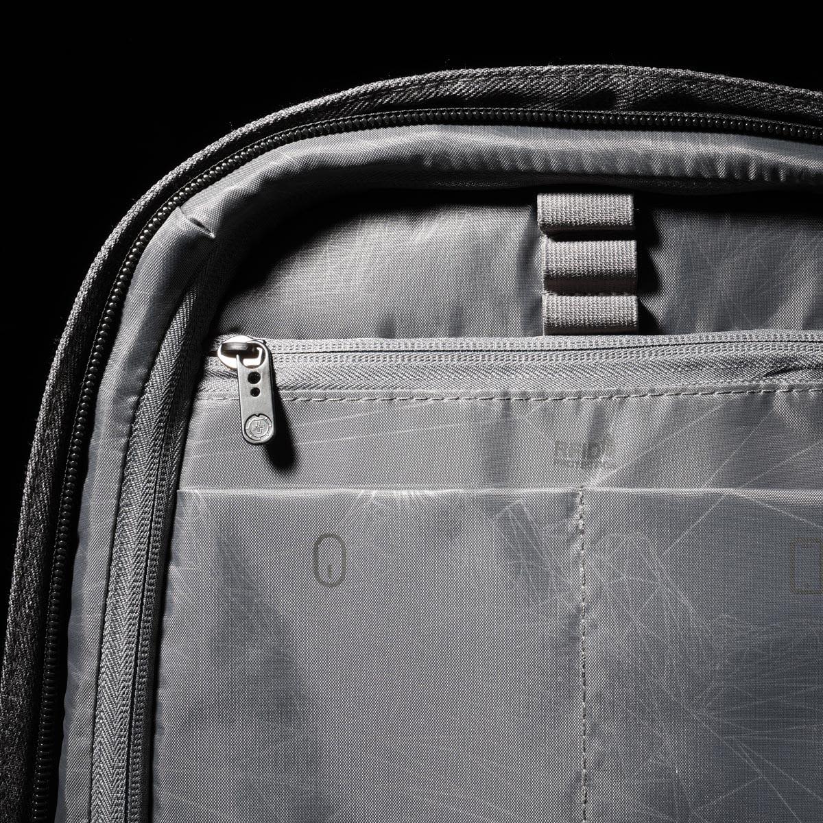 A grey backpack interior features zippered and compartmental storage with ergonomic design elements.
