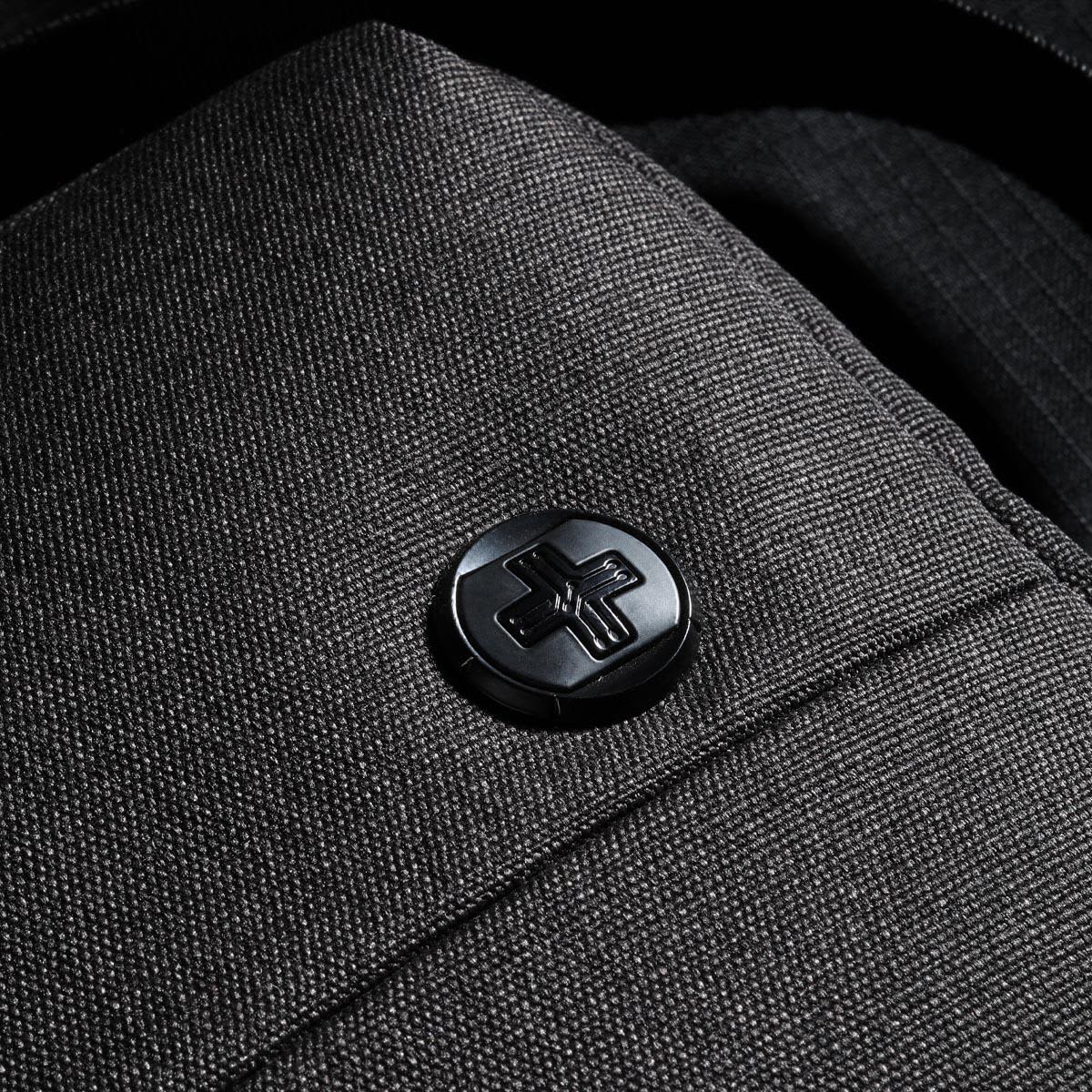 A dark grey shoulder bag with a textured fabric and a logo button. Ideal for carrying laptops and other essentials.