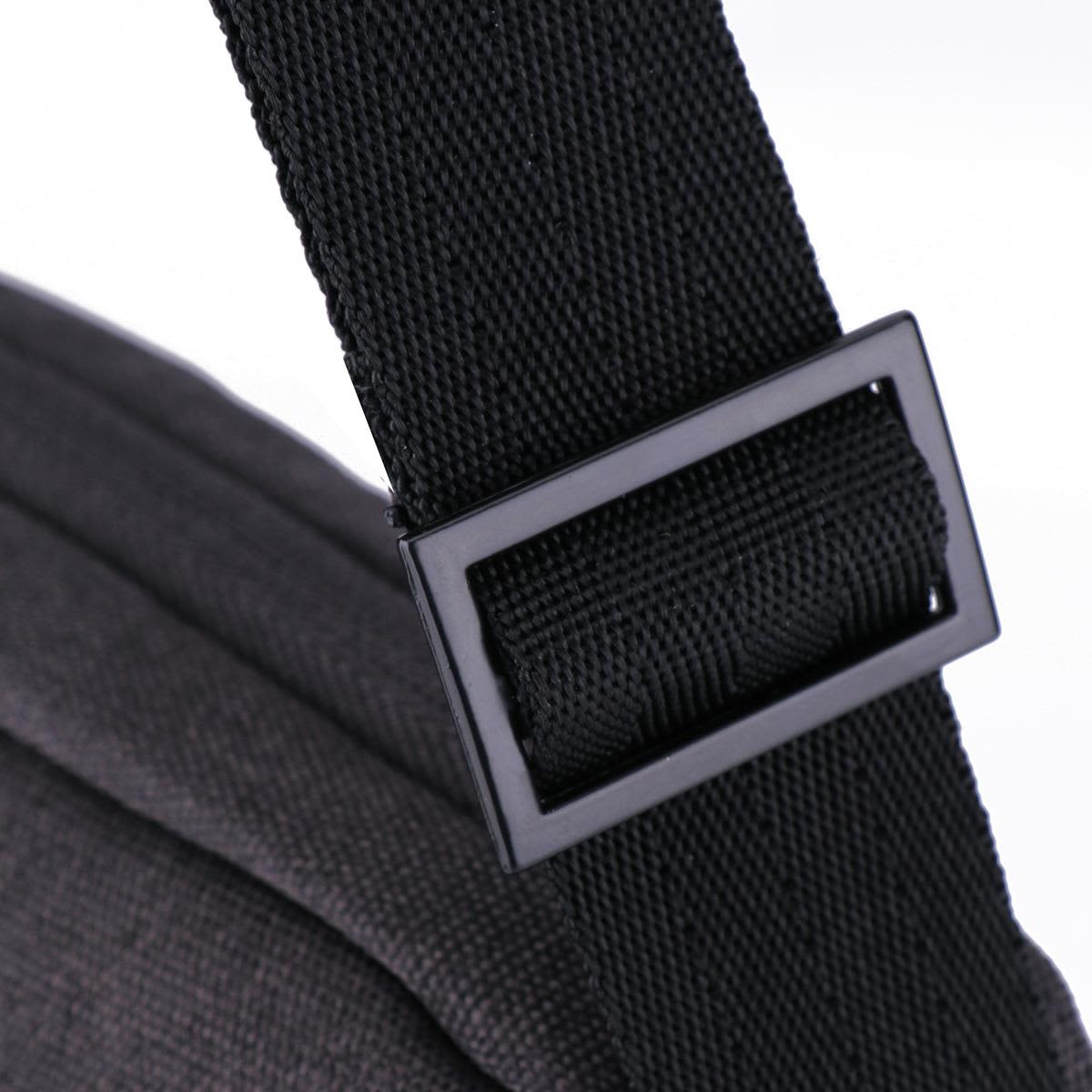 A black shoulder strap buckle featuring a textured fabric. The strap connects to a dark grey bag.